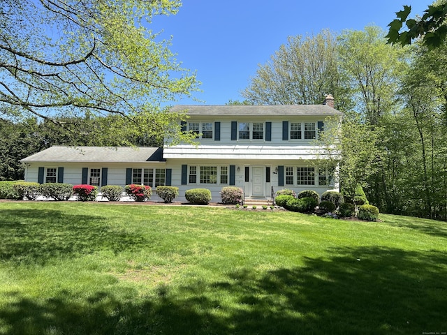 colonial house featuring a chimney and a front lawn