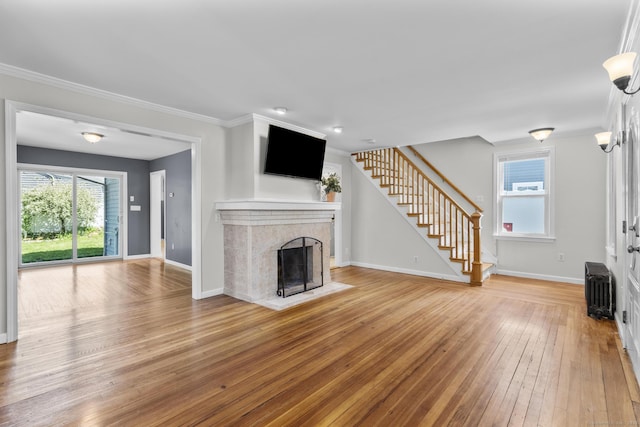 43 Atwater St, Milford, CT 06460 - unfurnished living room with stairs, light wood finished floors, radiator, a tiled fireplace, and crown molding