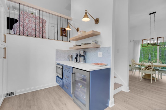 135 Gary Rd, Stamford, CT 06903 - indoor dry bar with beverage cooler, a high ceiling, light wood-style flooring, stainless steel microwave, and a chandelier