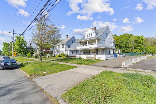view of front of house with covered porch, a front lawn, and a chimney