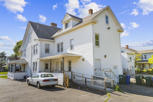 view of front of property with a chimney, roof with shingles, and covered porch