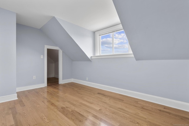 bonus room with light wood finished floors, lofted ceiling, and baseboards