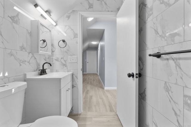 bathroom featuring toilet, vanity, tile walls, and wood finished floors