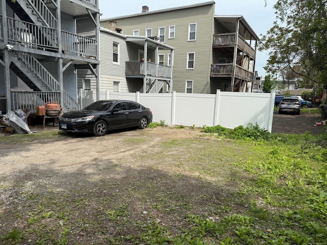 view of parking featuring fence and stairs