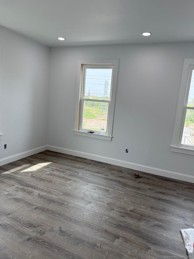 empty room featuring baseboards, dark wood-type flooring, and recessed lighting