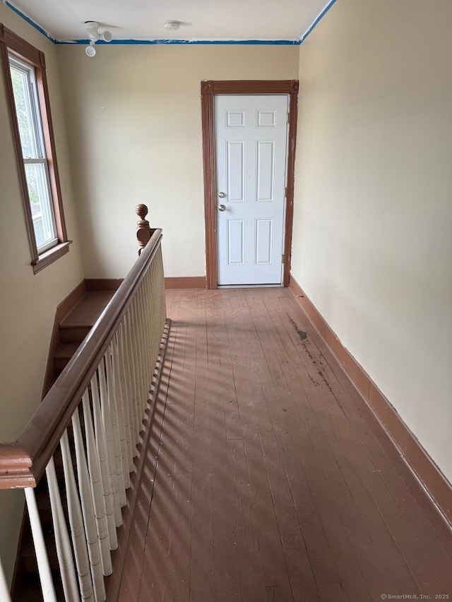 hall featuring an upstairs landing, baseboards, and hardwood / wood-style flooring