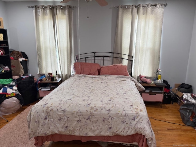 bedroom with multiple windows, wood finished floors, and ceiling fan