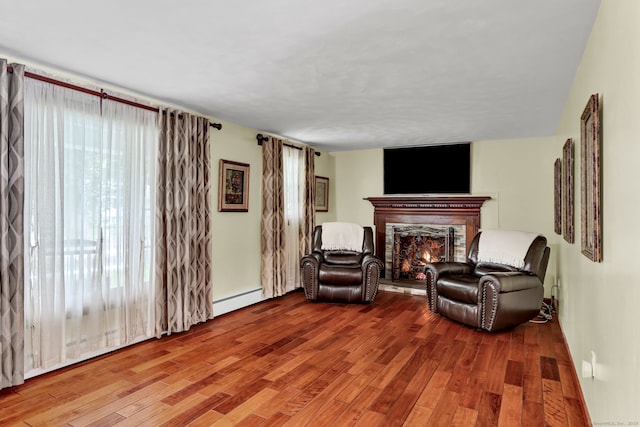 13 Carol St, Enfield, CT 06082 - living area with baseboard heating, a warm lit fireplace, and wood finished floors