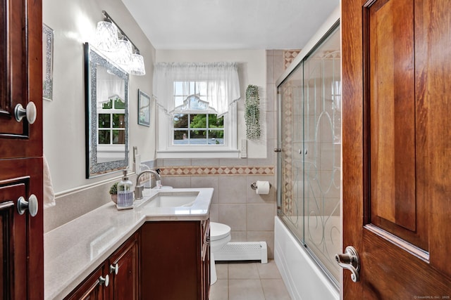 13 Carol St, Enfield, CT 06082 - bathroom featuring baseboard heating, tile patterned flooring, vanity, tile walls, and shower / bath combination with glass door