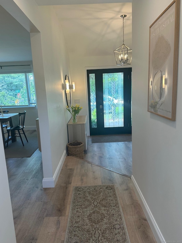 foyer featuring a chandelier, wood finished floors, and baseboards