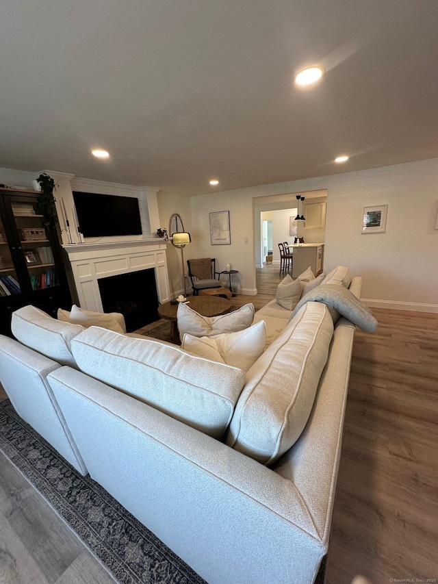 living area featuring baseboards, a fireplace, recessed lighting, and wood finished floors