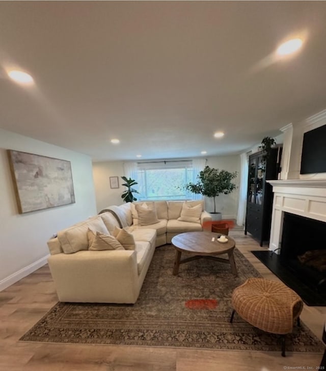 living room with light wood-type flooring, baseboards, a fireplace, and recessed lighting