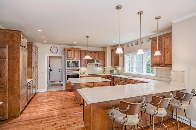 34 Avalon Dr, Middlebury, CT 06762 - kitchen with built in microwave, stainless steel oven, brown cabinets, light wood-type flooring, and light countertops