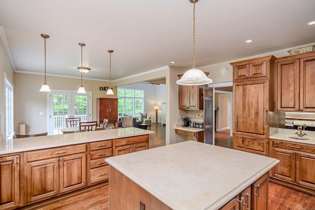34 Avalon Dr, Middlebury, CT 06762 - kitchen with light countertops, brown cabinetry, a kitchen island, light wood-type flooring, and ornamental molding