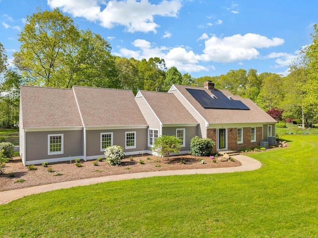 34 Willow Ln, East Lyme, CT 06333 - view of front facade with roof mounted solar panels, a front lawn, a chimney, roof with shingles, and brick siding