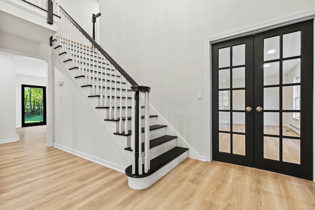 34 Willow Ln, East Lyme, CT 06333 - staircase featuring french doors, wood finished floors, baseboard heating, baseboards, and a towering ceiling