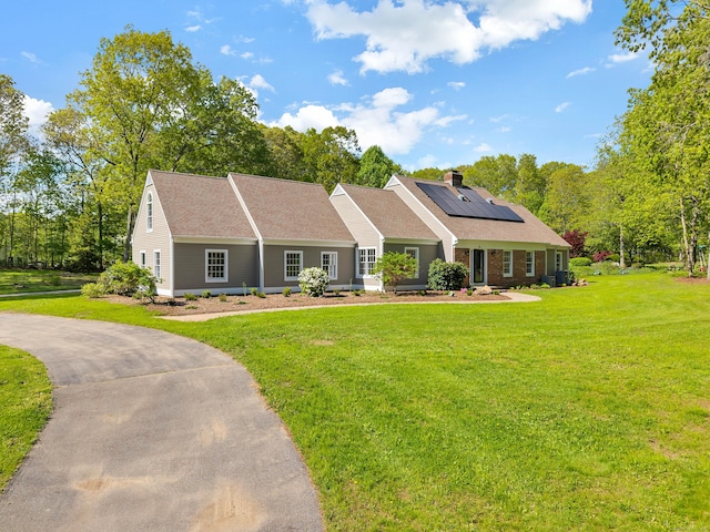 34 Willow Ln, East Lyme, CT 06333 - view of front facade with roof mounted solar panels, a front yard, a chimney, and roof with shingles