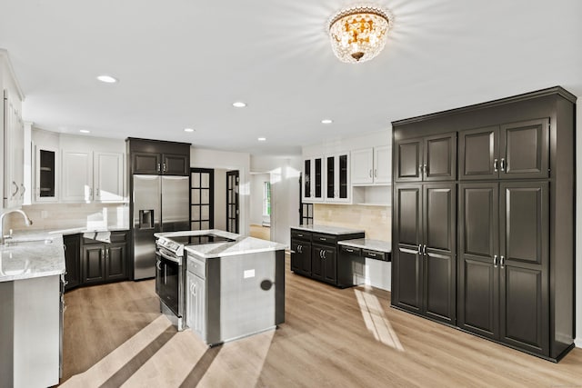 34 Willow Ln, East Lyme, CT 06333 - kitchen with stainless steel appliances, a sink, a kitchen island with sink, light wood-type flooring, and decorative backsplash