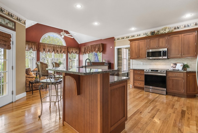 33 Pease Farm Rd, Ellington, CT 06029 - kitchen featuring stainless steel appliances, a kitchen bar, light wood-style floors, dark stone counters, and decorative backsplash