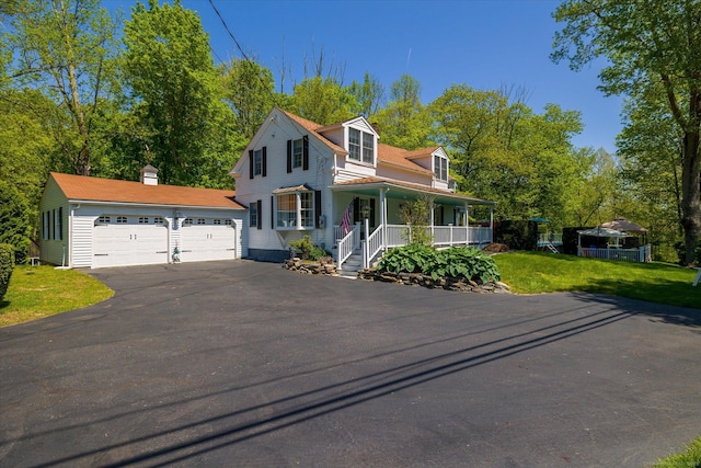 view of front facade featuring a porch, driveway, a garage, and a front lawn
