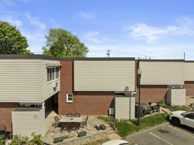 211 W Walk Unit 211, West Haven, CT 06516 - rear view of property featuring uncovered parking, a patio area, and brick siding