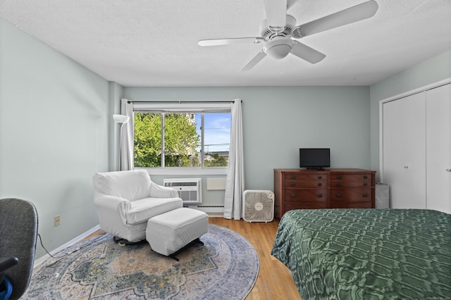 211 W Walk Unit 211, West Haven, CT 06516 - bedroom with baseboard heating, wood finished floors, a textured ceiling, a ceiling fan, and a closet