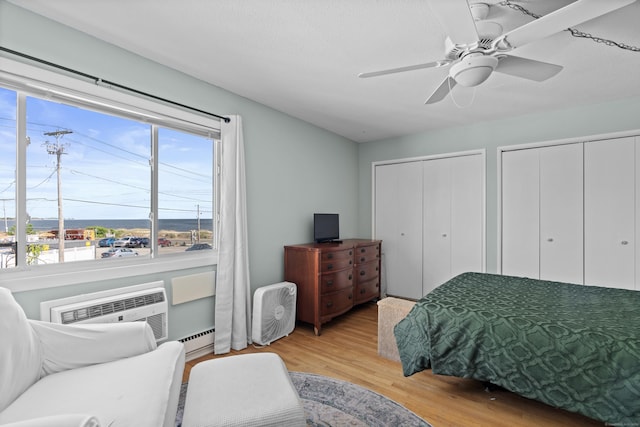 211 W Walk Unit 211, West Haven, CT 06516 - bedroom with a baseboard radiator, multiple closets, wood finished floors, ceiling fan, and a wall mounted AC