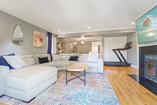 living area with wood finished floors, crown molding, a fireplace with flush hearth, recessed lighting, and baseboards