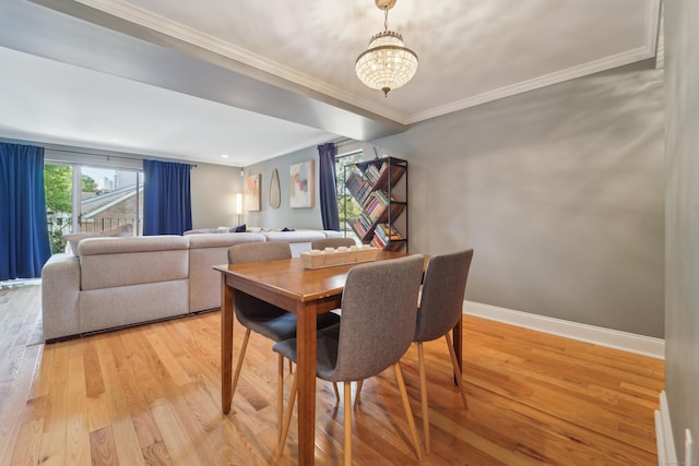 dining space featuring light wood finished floors, a chandelier, crown molding, and baseboards