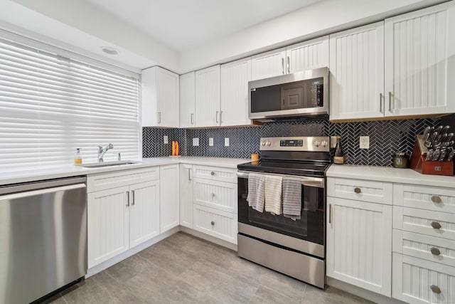 kitchen with appliances with stainless steel finishes, a sink, light countertops, and backsplash