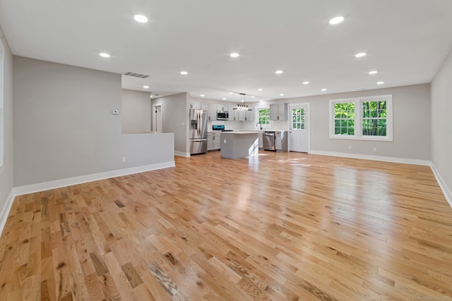 26 Maple Ave, North Haven, CT 06473 - unfurnished living room with recessed lighting, light wood-style flooring, baseboards, a chandelier, and a sink