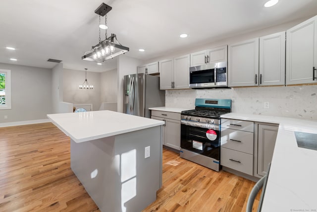 26 Maple Ave, North Haven, CT 06473 - kitchen featuring appliances with stainless steel finishes, a center island, tasteful backsplash, light wood-style floors, and hanging light fixtures