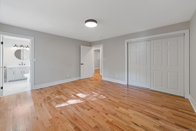 26 Maple Ave, North Haven, CT 06473 - unfurnished bedroom featuring light wood-style flooring, baseboards, a closet, a sink, and ensuite bath