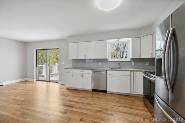 kitchen with stainless steel appliances, tasteful backsplash, a sink, and light wood-style flooring