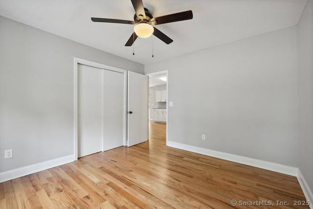 unfurnished bedroom with baseboards, a closet, light wood-style floors, and a ceiling fan
