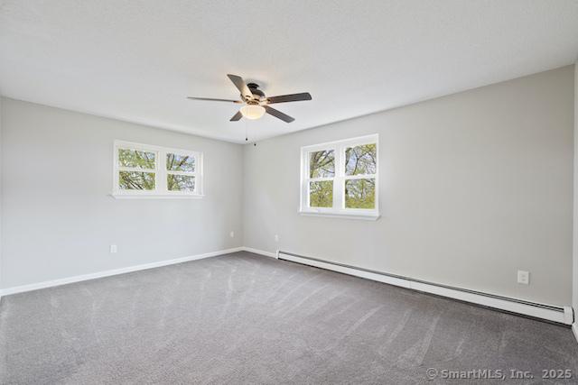 empty room with a baseboard heating unit, plenty of natural light, a ceiling fan, and carpet flooring