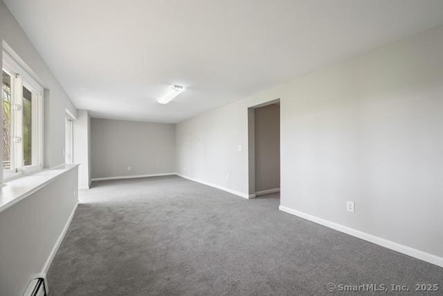 empty room featuring baseboard heating, carpet flooring, and baseboards