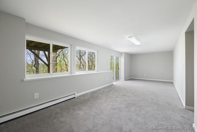 empty room featuring a baseboard radiator, carpet floors, and baseboards