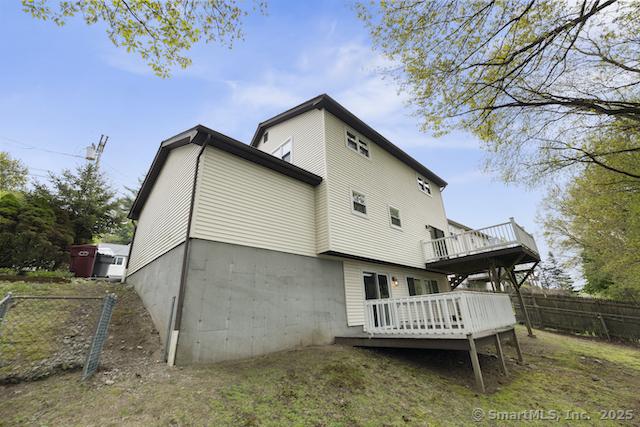 rear view of house featuring a deck and fence