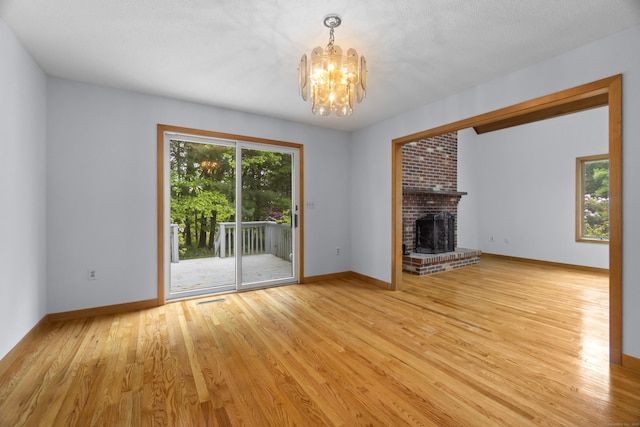2 Meadowview Ln, Norwich, CT 06360 - unfurnished living room featuring a chandelier, wood finished floors, a fireplace, and baseboards