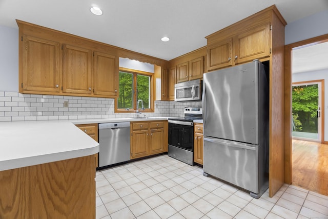 2 Meadowview Ln, Norwich, CT 06360 - kitchen with appliances with stainless steel finishes, tasteful backsplash, brown cabinetry, light countertops, and a sink
