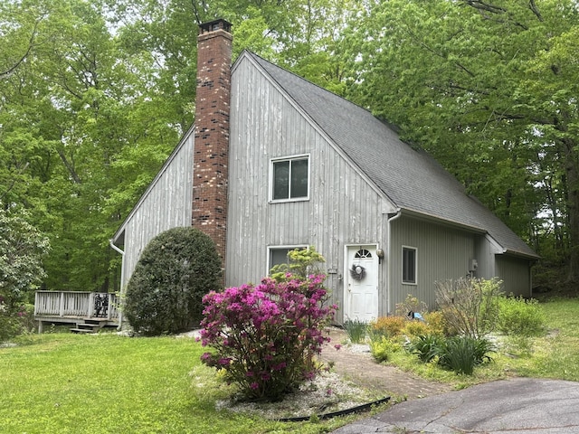 70 Lynn Rd, Essex, CT 06442 - view of side of home with a chimney, roof with shingles, a detached garage, a wooden deck, and a lawn