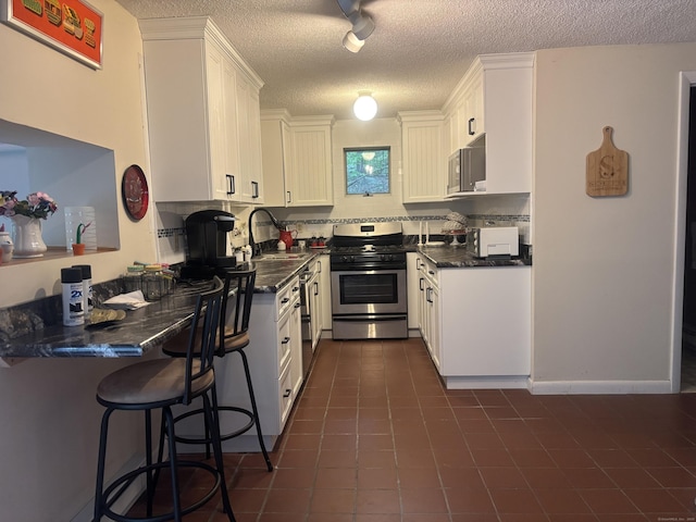 70 Lynn Rd, Essex, CT 06442 - kitchen with stainless steel appliances, a sink, a textured ceiling, dark countertops, and white cabinets