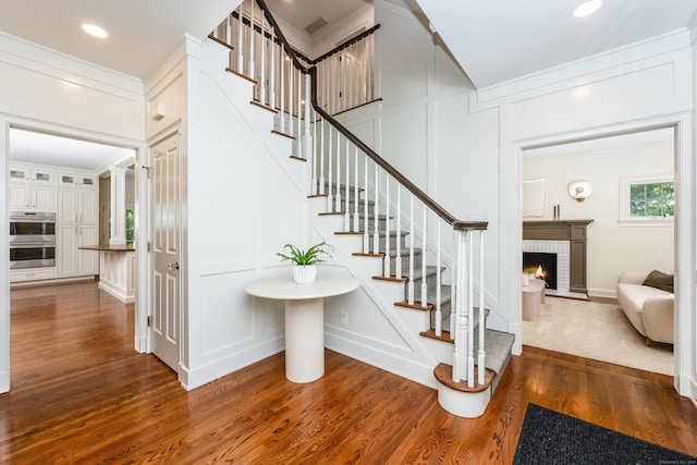 21 Park Pl, Darien, CT 06820 - staircase featuring a decorative wall, wood finished floors, a fireplace, and crown molding