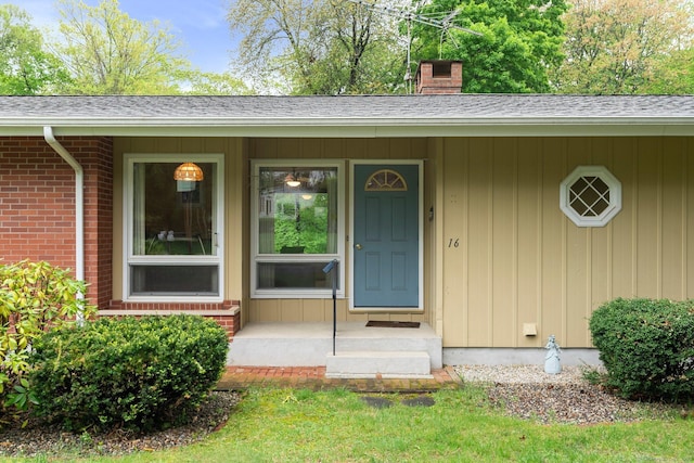 16 Ellsworth Rd, East Windsor, CT 06016 - view of exterior entry featuring a chimney, a porch, roof with shingles, and brick siding
