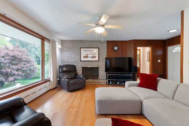 16 Ellsworth Rd, East Windsor, CT 06016 - living area featuring a ceiling fan, light wood-style flooring, a fireplace, a baseboard heating unit, and wooden walls