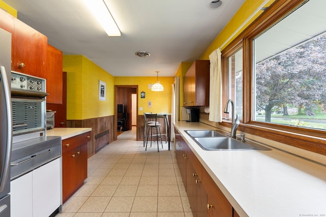 16 Ellsworth Rd, East Windsor, CT 06016 - kitchen with a sink, light countertops, a wainscoted wall, light tile patterned flooring, and hanging light fixtures