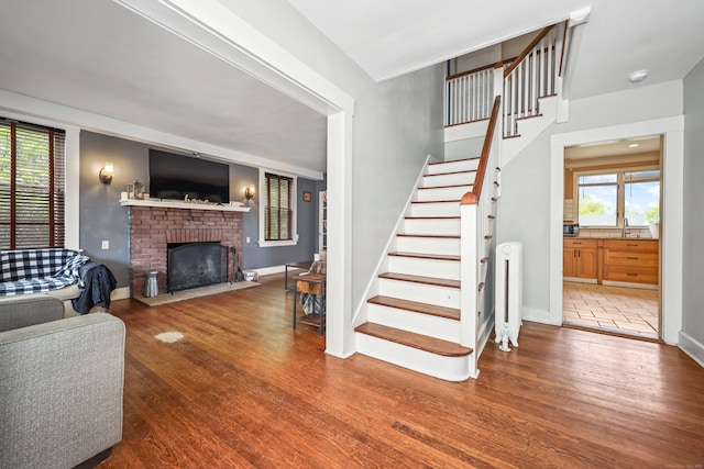 30 Birchwood St, Waterbury, CT 06708 - living area featuring radiator heating unit, wood finished floors, stairs, a fireplace, and baseboards