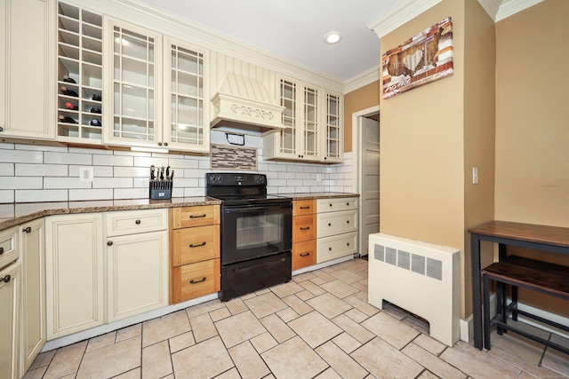 30 Birchwood St, Waterbury, CT 06708 - kitchen with black / electric stove, radiator heating unit, crown molding, cream cabinetry, and tasteful backsplash