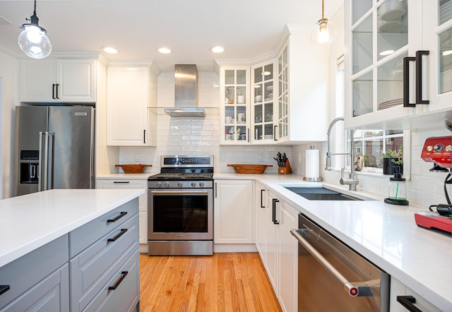 23 Hale St, Westport, CT 06880 - kitchen with appliances with stainless steel finishes, wall chimney range hood, a sink, light wood-type flooring, and hanging light fixtures